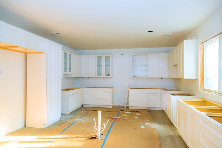 Kitchen renovation in progress with construction materials and empty cabinets during installation