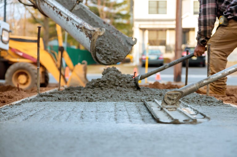 Workers pouring and leveling fresh concrete for sidewalk during construction