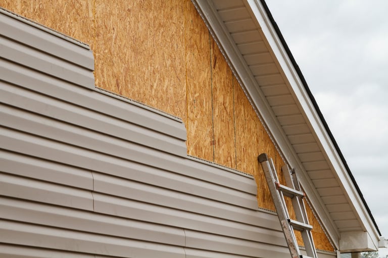 New vinyl siding being installed on residential house, old siding replacement job